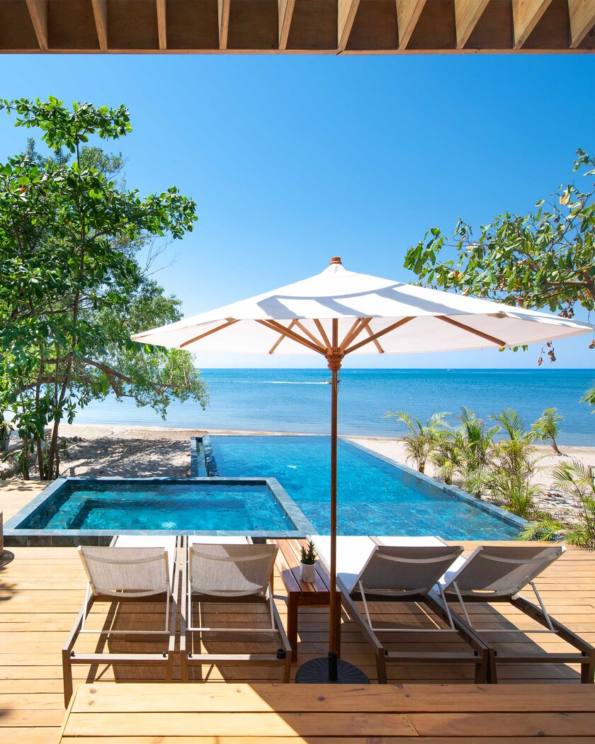 Loungers and parasol by the pool, facing the sea