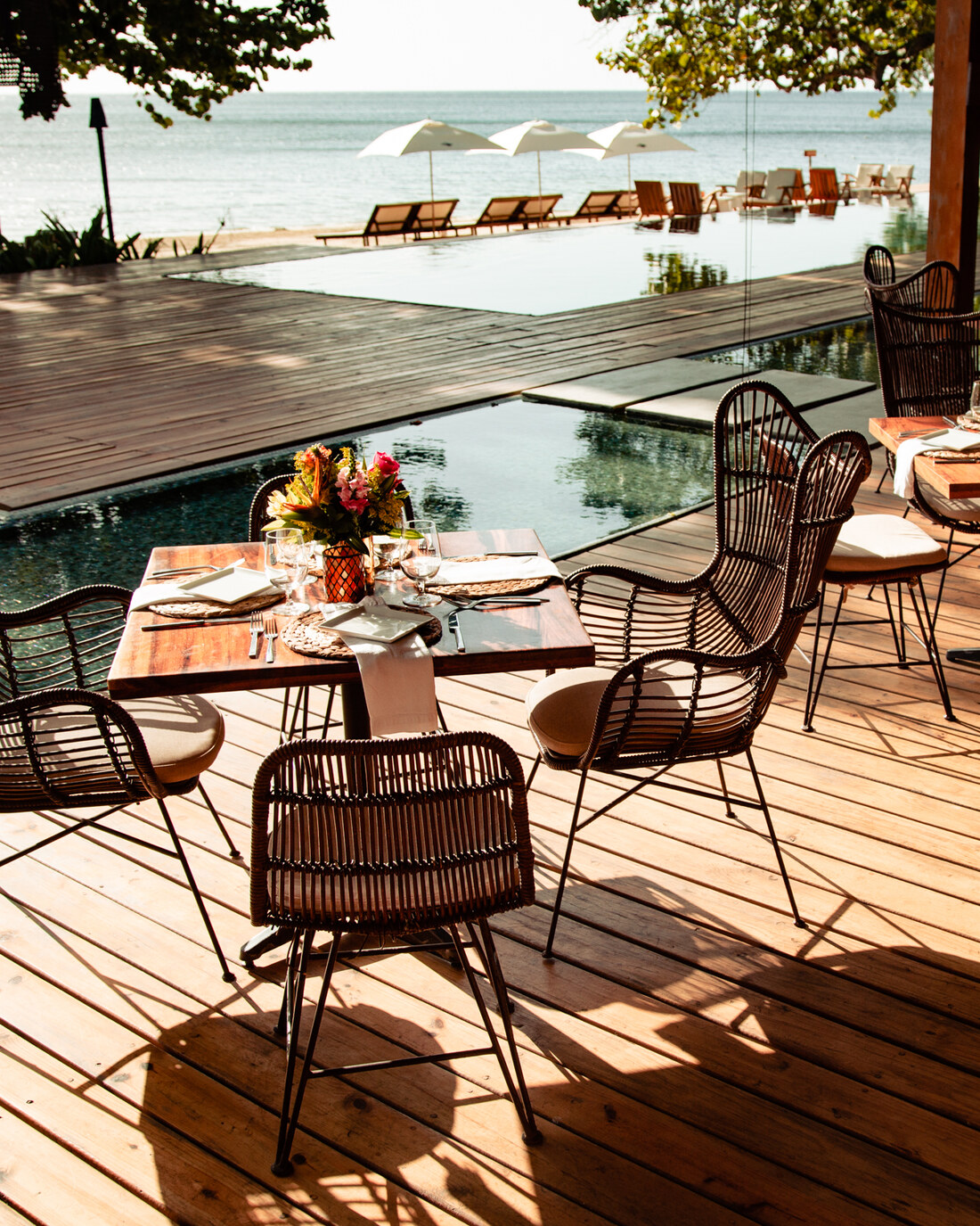 Luna Muna's deck beside the pool, tables set under the trees with the sea behind