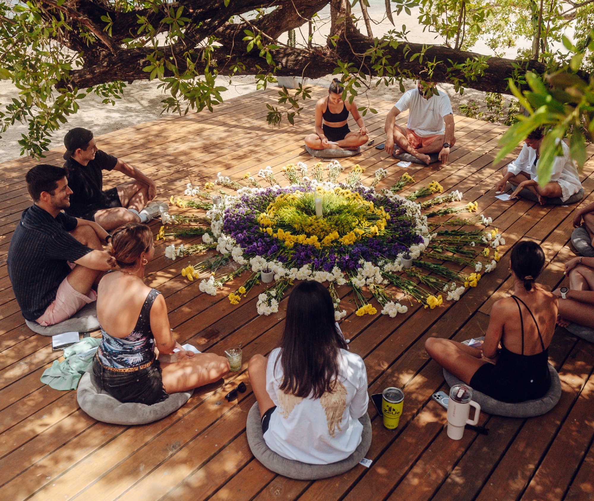 A retreat circle gathered around a flower mandala on the deck