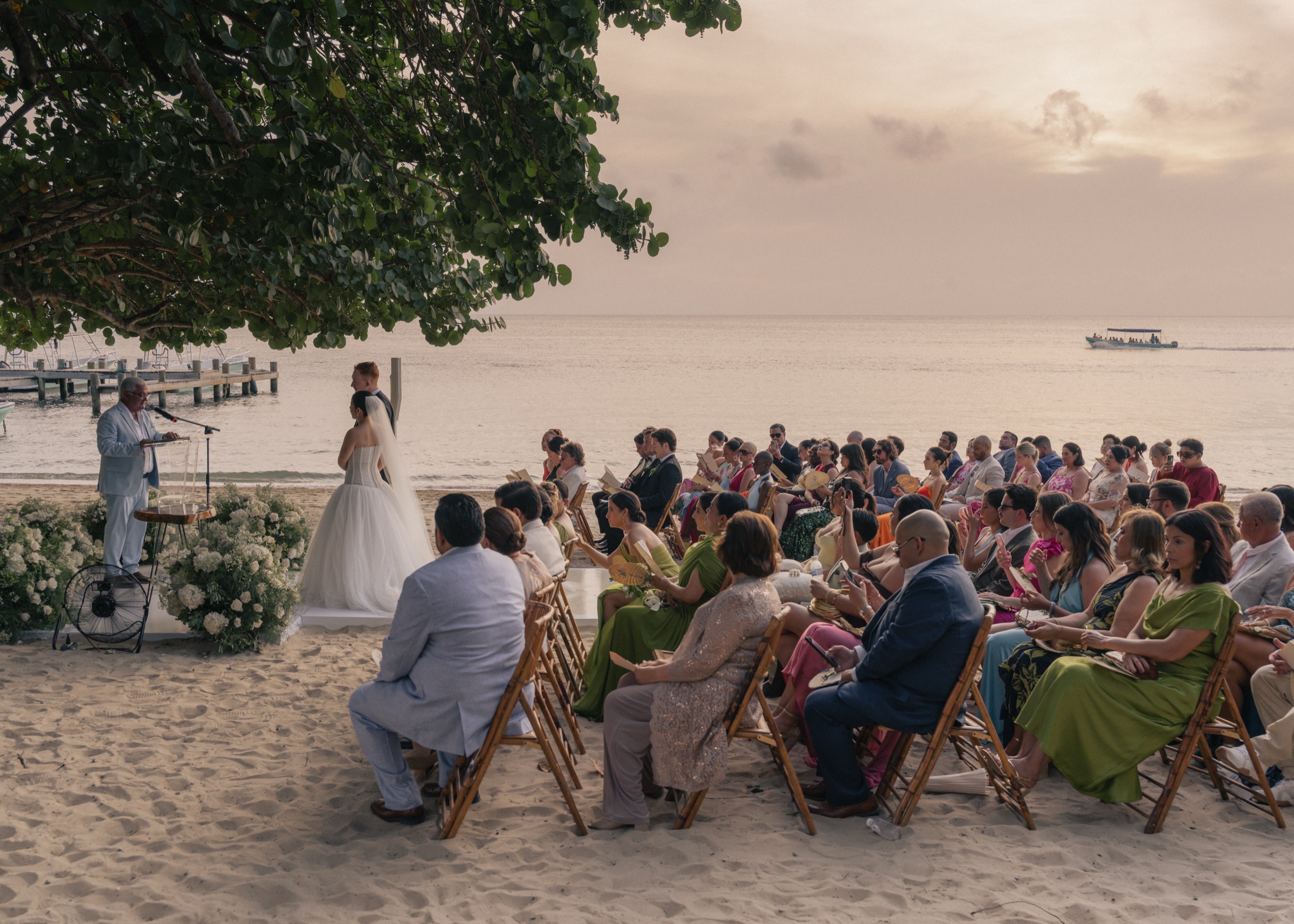 A ceremony under the almond tree, guests seated on the sand